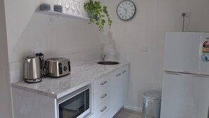 Eine moderne Küche mit Edelstahl-Toaster, Wasserkocher und Mikrowelle, einem Spülbecken, einer Uhr und einem Kühlschrank.