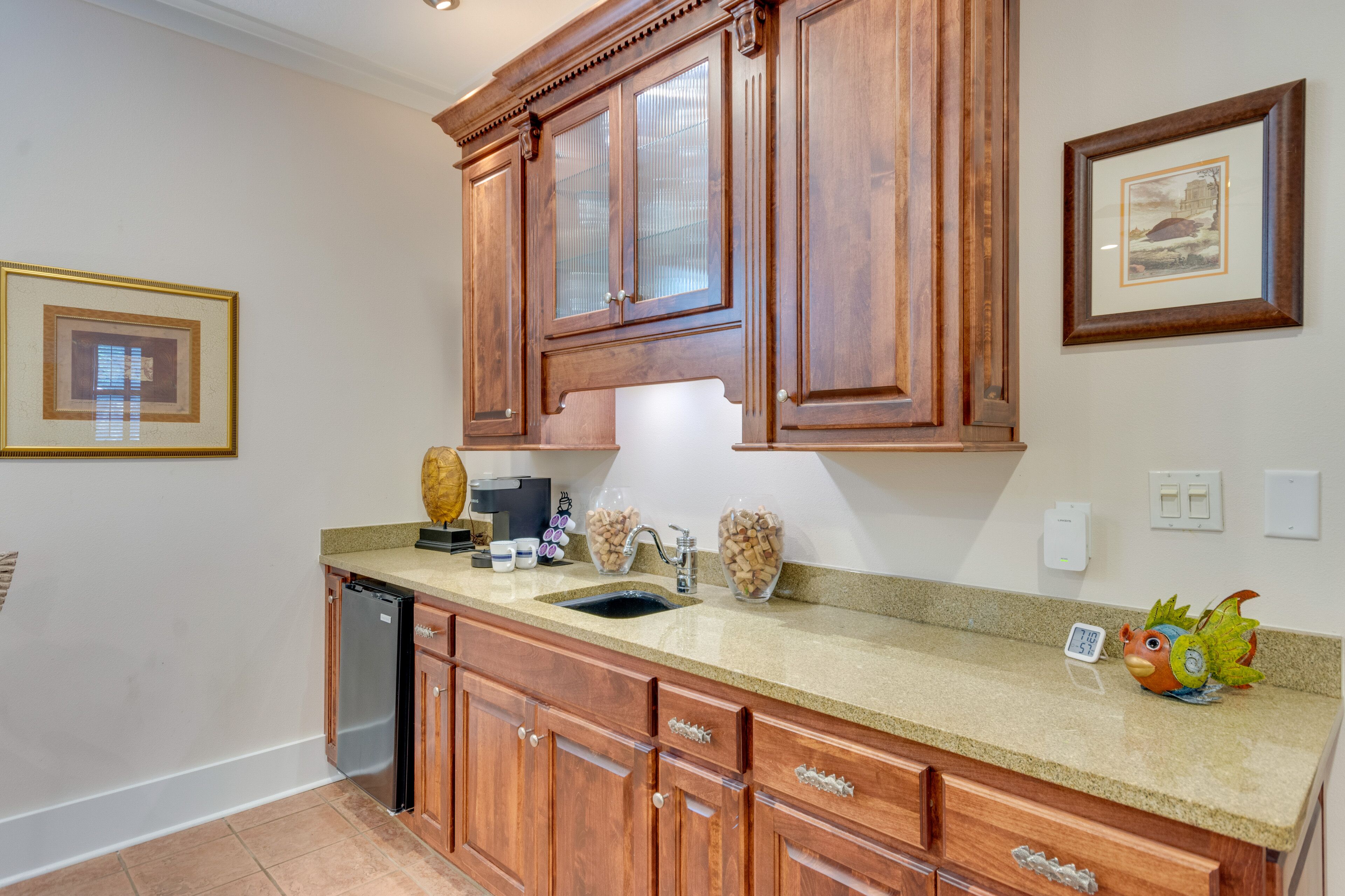 A kitchen with wooden cabinets, a granite countertop, a dishwasher, and a decorative bird figurine.