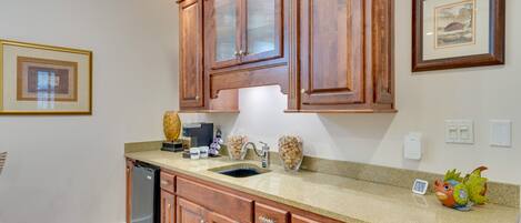 A kitchen with wooden cabinets, a granite countertop, a dishwasher, and a decorative bird figurine.