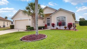 A two-story house with a garage, a well-maintained lawn, and a palm tree. - 4 bedrooms home with private pool- 15 min from Disney (Davenport)
