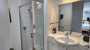A modern bathroom with a glass-enclosed shower, a white sink, and a large mirror. - Blencathra Coastal Spa Getaway (Currie King Island)