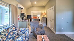 A living room with a sofa, armchair, and coffee table. There is a kitchen area with a microwave and a sink. The room has a door leading to another space. - 2 Mi to Branson Strip: Cozy Cottage w/ Fire Pit! (Branson)