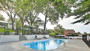 A swimming pool with a green deck, a covered seating area, and a staircase leading to a building. - 2 Mi to Branson Strip: Cozy Cottage w/ Fire Pit! (Branson)