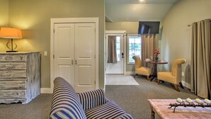 A living room with a sofa, a lamp, a dresser, a door, a television, and a dining area with chairs and a table. - 2 Mi to Branson Strip: Cozy Cottage w/ Fire Pit! (Branson)