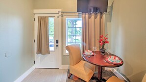 A dining area with a table set for two, a chair, and a door with curtains. - 2 Mi to Branson Strip: Cozy Cottage w/ Fire Pit! (Branson)