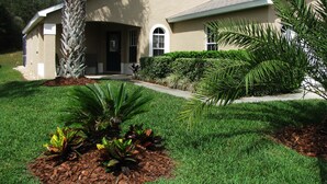 A single-story house with a beige exterior, a front porch, and a well-maintained lawn.
