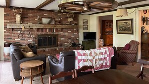 Una sala de estar acogedora con chimenea de ladrillo, muebles de cuero y ventilador de techo.
