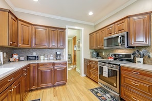 A kitchen with wooden cabinets, a stainless steel stove, a microwave, and a coffee maker. - Hot Tub & Mtn Views: Beautiful Bryson City Home (Bryson City)