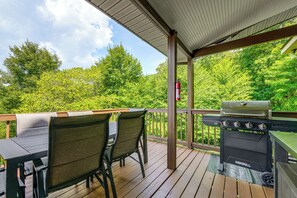 A covered outdoor deck with a grill and seating area. - Hot Tub & Mtn Views: Beautiful Bryson City Home (Bryson City)