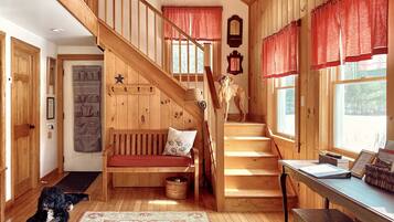A wooden interior with a staircase, a bench, and a dog.