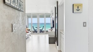 Un moderno cuarto de hotel con vista al océano, un letrero de playa y una obra de arte con un ancla enmarcada.