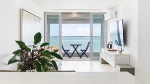 Una sala de estar moderna con un amplio ventanal con vistas a un cuerpo de agua, un televisor de pantalla plana y una planta en maceta.