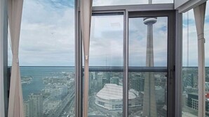 A high-rise building with a large window offering a panoramic view of a cityscape, including a prominent tower and a stadium.