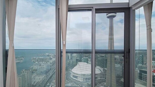 Un immeuble de grande hauteur doté d’une grande fenêtre offrant une vue panoramique sur le paysage urbain, notamment une tour imposante et un stade.