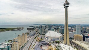 A high-rise building with a distinctive tower, surrounded by a dense urban area with various buildings and a waterfront.