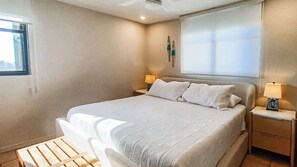 A hotel room with a bed, two bedside tables, a window, and a ceiling fan.