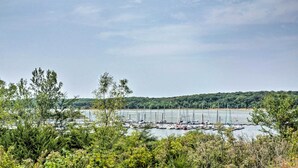 En lysthavn med fortøjede både, omgivet af frodig vegetation og et bakket landskab i baggrunden.