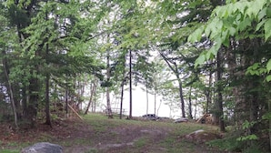 Metsäinen alue, jossa on sorapolku, suuria kiviä ja puita.