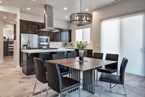 A modern kitchen with dark wood cabinets, stainless steel appliances, and a central island with seating. - Panoramic Golf & Canyon Views - 3BR on the 18th (St. George)