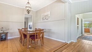 A dining area with a wooden table and chairs, a chandelier, and a framed picture on the wall. - Bunya@Maleny Farm House (Witta)