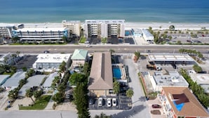 A coastal hotel with multiple floors, a parking lot, and a view of the beach and ocean.