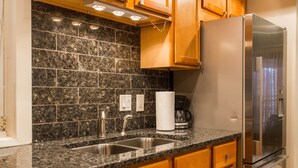 A kitchen with granite countertops, stainless steel appliances, wooden cabinets, and a tiled backsplash. - Heart of the City Group Hub • Patio • Fireplace • Parking (Chicago)