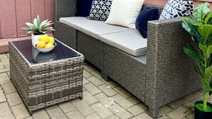 A wicker sofa with cushions and a small table with a bowl of lemons. - Heart of the City Group Hub • Patio • Fireplace • Parking (Chicago)