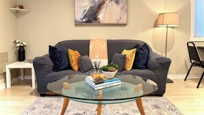 A modern living room with a grey sofa, a glass coffee table, and a minimalist decor. - Heart of the City Group Hub • Patio • Fireplace • Parking (Chicago)