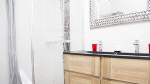 Ein Badezimmer mit Dusche, einem Spiegel mit dekorativem Rahmen und einem Holzausleger mit schwarzer Arbeitsplatte.