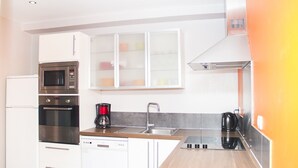 Eine moderne Küche mit weißen Schränken, Edelstahlgeräten, einer Holz Arbeitsplatte und einem eingebauten Backofen.