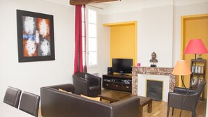 Ein Wohnzimmer mit einer Couch, Sesseln, einem Fernseher und einem Kamin.