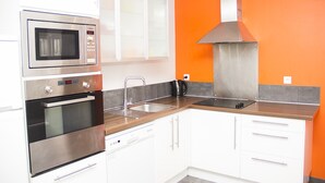 Eine moderne Küche mit Edelstahlgeräten, weißen Schränken und einer grauen Arbeitsplatte.