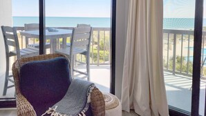 A balcony with a view of the ocean, a wicker chair, and a table with chairs. - Crescent C4B - Nicely Furnished - Oceanfront - Private Balcony (Pawleys Island)