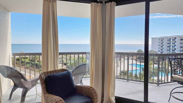 A balcony with wicker chairs, a view of the sea, and a pool. - Crescent C4B - Nicely Furnished - Oceanfront - Private Balcony (Pawleys Island)