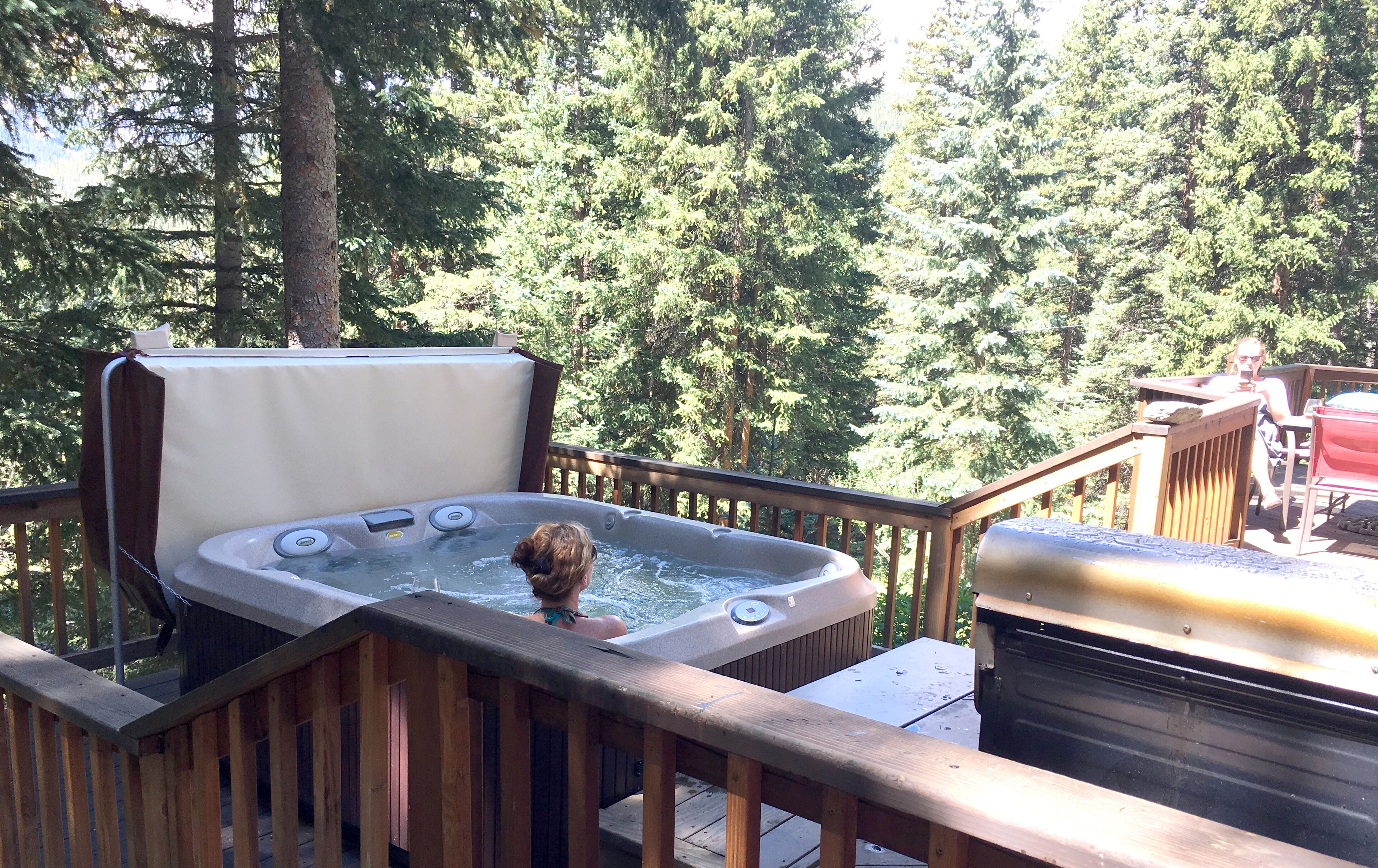 A hot tub on a wooden deck with a view of a forest.