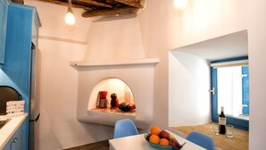 Una cocina moderna con horno empotrado, un frutero sobre la encimera y una botella de vino en el alféizar.