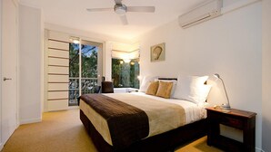A bedroom with a bed, bedside table, lamp, and a view of the outdoors.