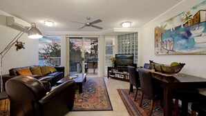 A living room with a sofa, coffee table, TV, and dining area with chairs and a table.