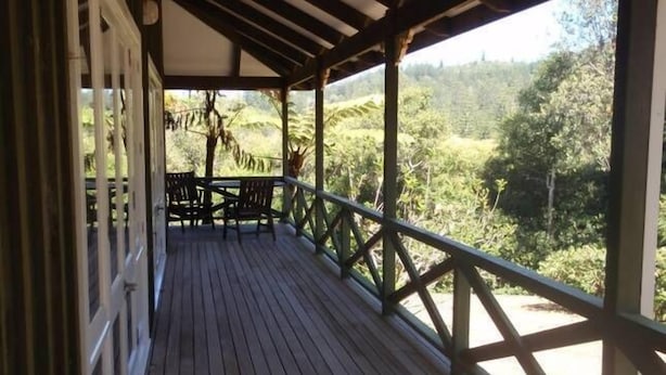 A wooden deck with a railing, overlooking a lush green landscape.