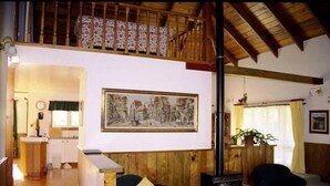 A spacious living area with a wooden ceiling, a large framed picture on the wall, and a cozy seating arrangement.