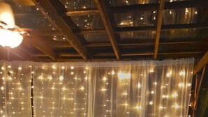 A dining area with a table set for four, surrounded by white curtains with string lights.