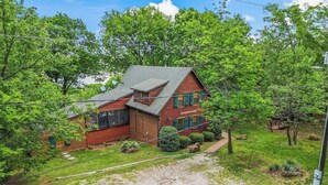 A log cabin with a sloped roof, surrounded by lush greenery and trees.