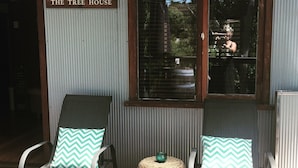 Zwei Lounge-Stühle mit passenden Kissen, ein Korbsitzhocker und ein Fenster mit Jalousien.