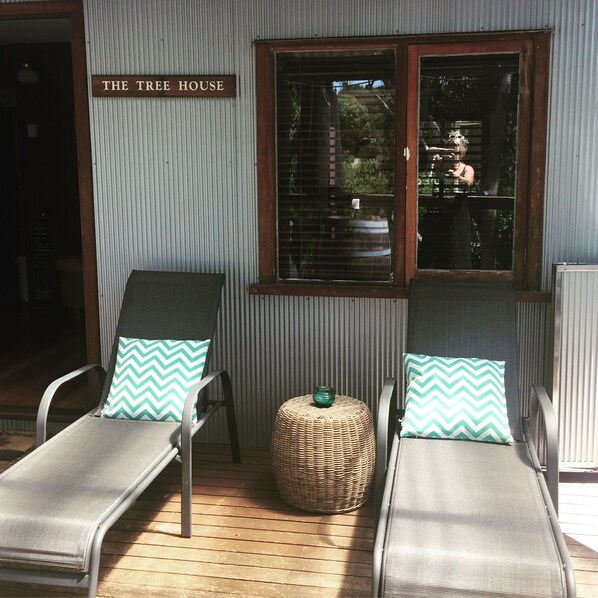 Two lounge chairs with matching cushions, a wicker ottoman, and a window with a view of the outdoors.