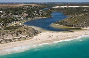 An aerial view of a coastal area with a beach, a river, and a small town.
