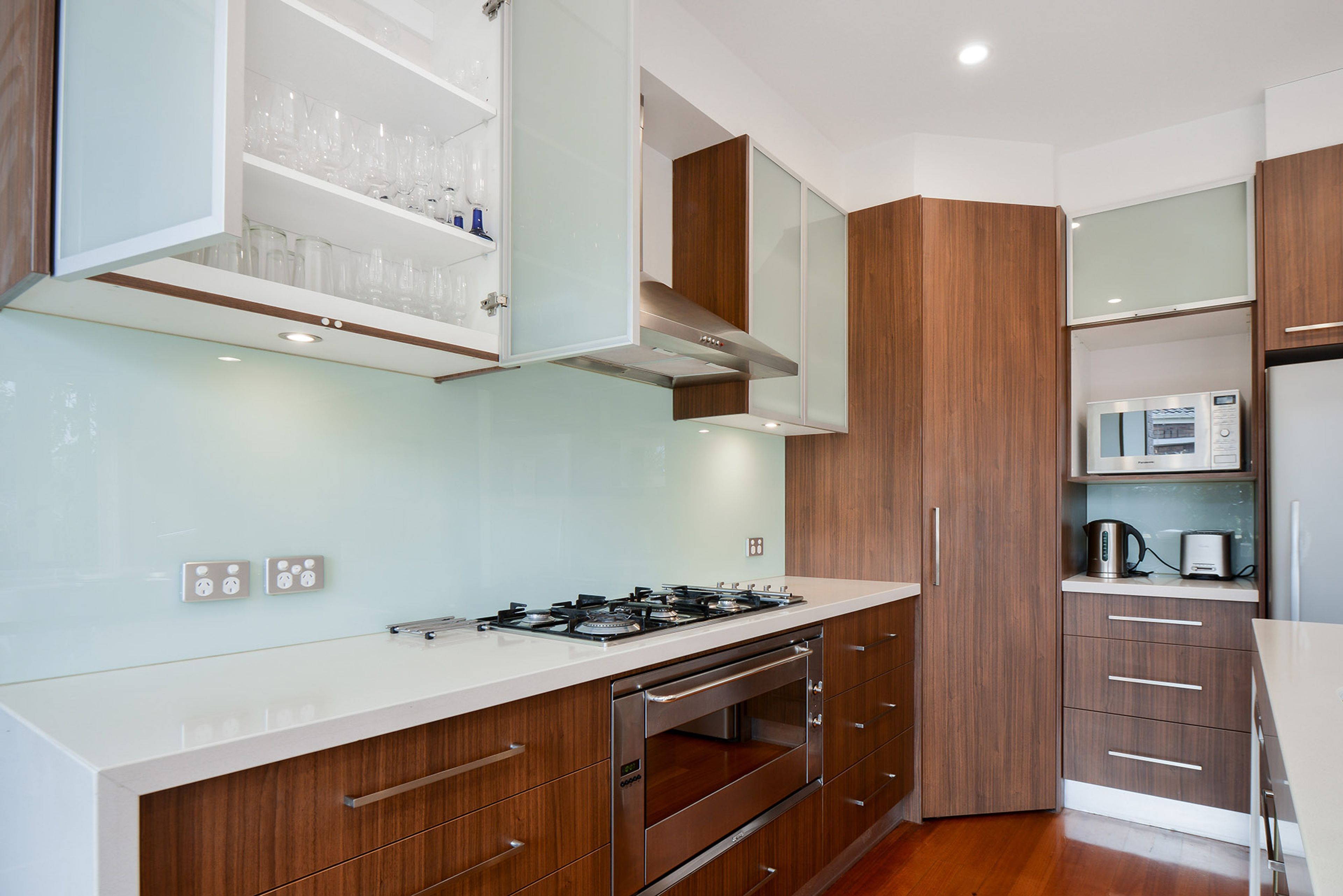 A modern kitchen with a gas stove, wooden cabinets, and a built-in microwave.