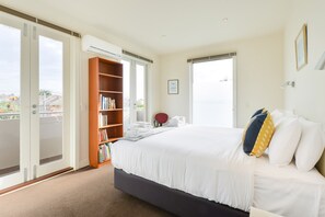 Ein Hotelzimmer mit einem Bett, einem Bücherregal, einer Tür, die auf einen Balkon führt, und einem Fenster.