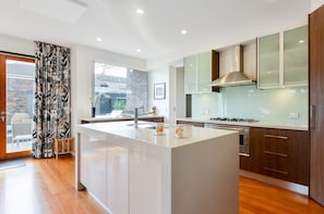 A modern kitchen with a central island, stainless steel appliances, and wooden cabinetry. - Maple on Kent Pet Friendly Glen Iris Retreat (Glen Iris)