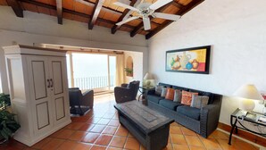 A spacious living area with a balcony, wicker furniture, a painting, and a ceiling fan. - Great Penthouse at El Dorado 3BD Penthouse for rent in Los Muertos Beach, Puerto (Puerto Vallarta)