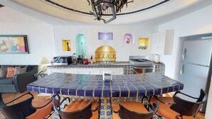 A kitchen with a central island, a stove, a refrigerator, and a dining area with chairs. - Great Penthouse at El Dorado 3BD Penthouse for rent in Los Muertos Beach, Puerto (Puerto Vallarta)